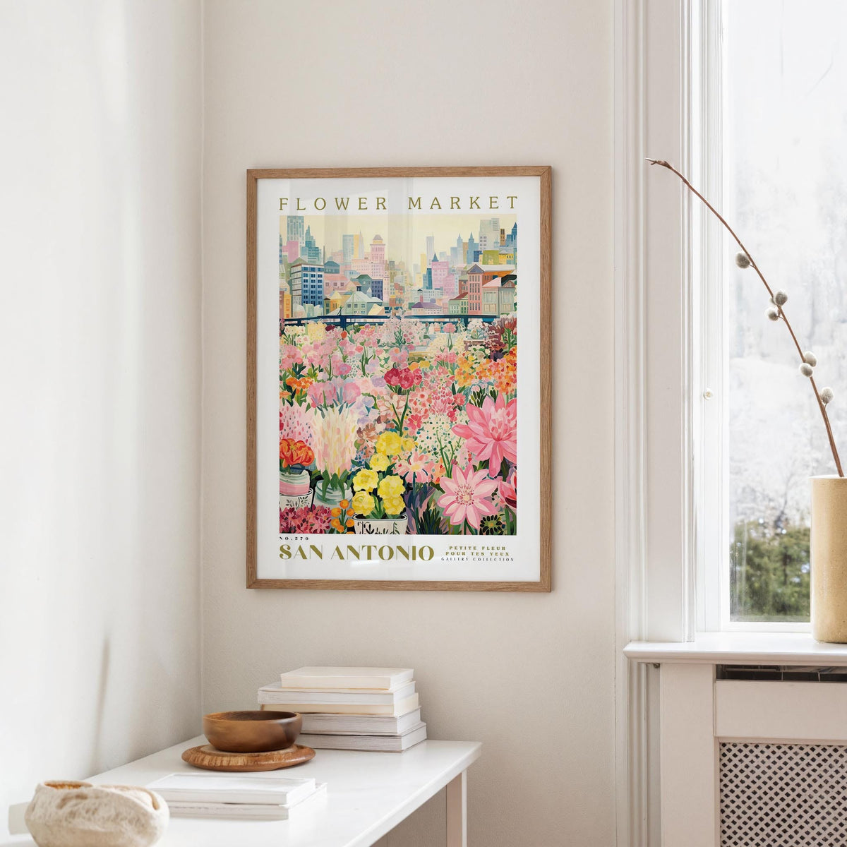 a framed poster of a colorful flower market in San Antonio, Texas, hanging on a wall.