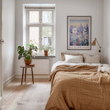 a cozy bedroom with a large bed, a nightstand with a plant, and a framed poster of a flower market in Denver.