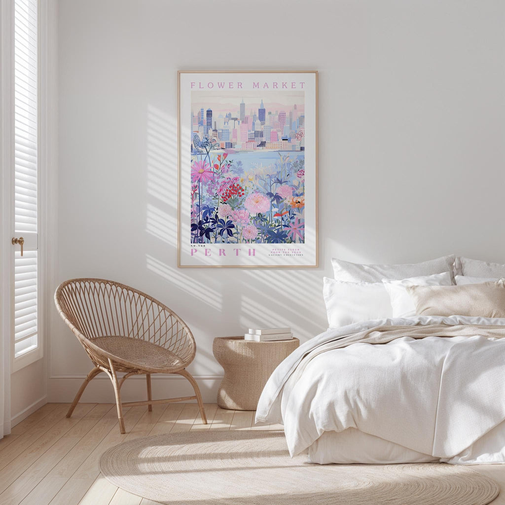 a bedroom with a bed, a woven chair, and a framed poster of a cityscape on the wall.