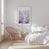 a bedroom with a bed, a woven chair, and a framed poster of a cityscape on the wall.