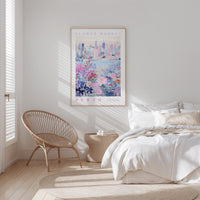 a bedroom with a bed, a woven chair, and a framed poster of a cityscape on the wall.