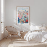 a bedroom with a large poster of a cityscape hanging on the wall, a woven chair, and a bed with white bedding.