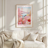a framed poster of a colorful floral scene hanging on a wall above a white couch with a blanket draped over it.