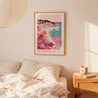 a bedroom with a framed poster of a beach scene hanging on the wall above a bed with striped pillows.