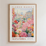 The image is a framed poster depicting a vibrant and colorful flower market in the city of Alexandria, with buildings and flowers in the background.
