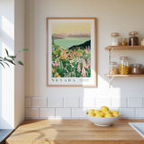a kitchen scene with a framed print of a colorful landscape of flowers and mountains hanging on the wall above a wooden countertop. On the countertop, there is a bowl of lemons and a plant, and a shelf with various jars and containers.