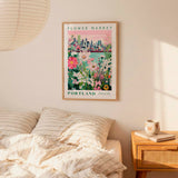 a bedroom setting with a framed poster of a cityscape and flowers hanging on the wall above a bed with striped pillows.