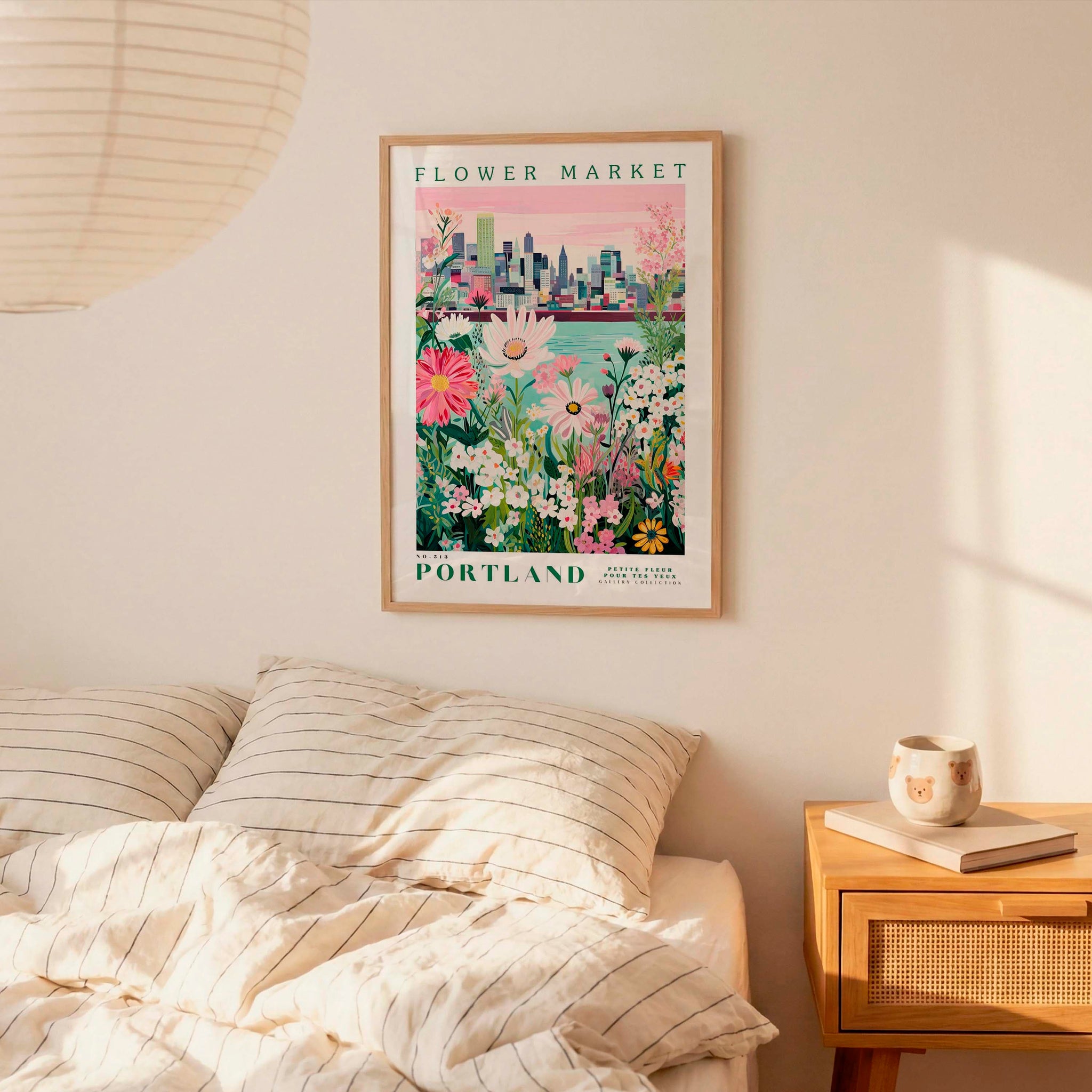 a bedroom setting with a framed poster of a cityscape and flowers hanging on the wall above a bed with striped pillows.