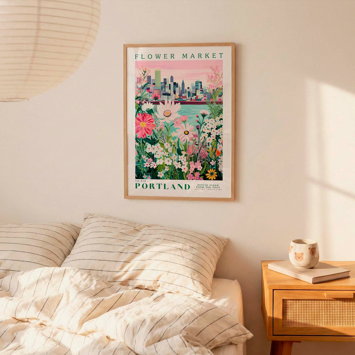 a bedroom setting with a framed poster of a cityscape and flowers hanging on the wall above a bed with striped pillows.