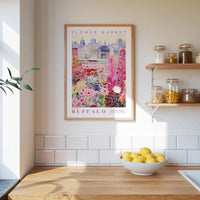 a framed poster of a flower market in Buffalo, New York, with a wooden shelf below it holding various jars and containers.