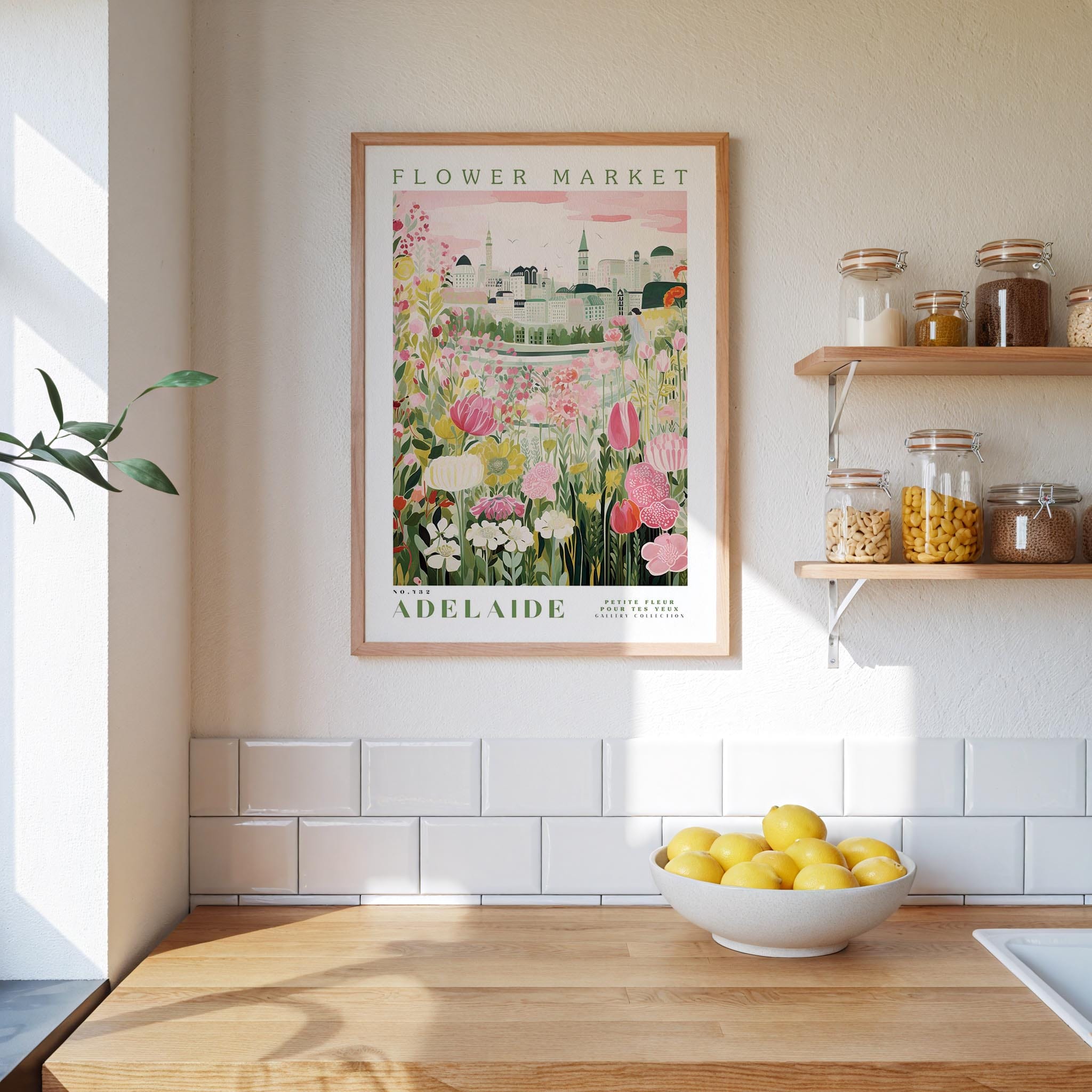 a framed poster of a flower market in Adelaide, Australia, hanging on a wall above a wooden counter with a bowl of lemons.