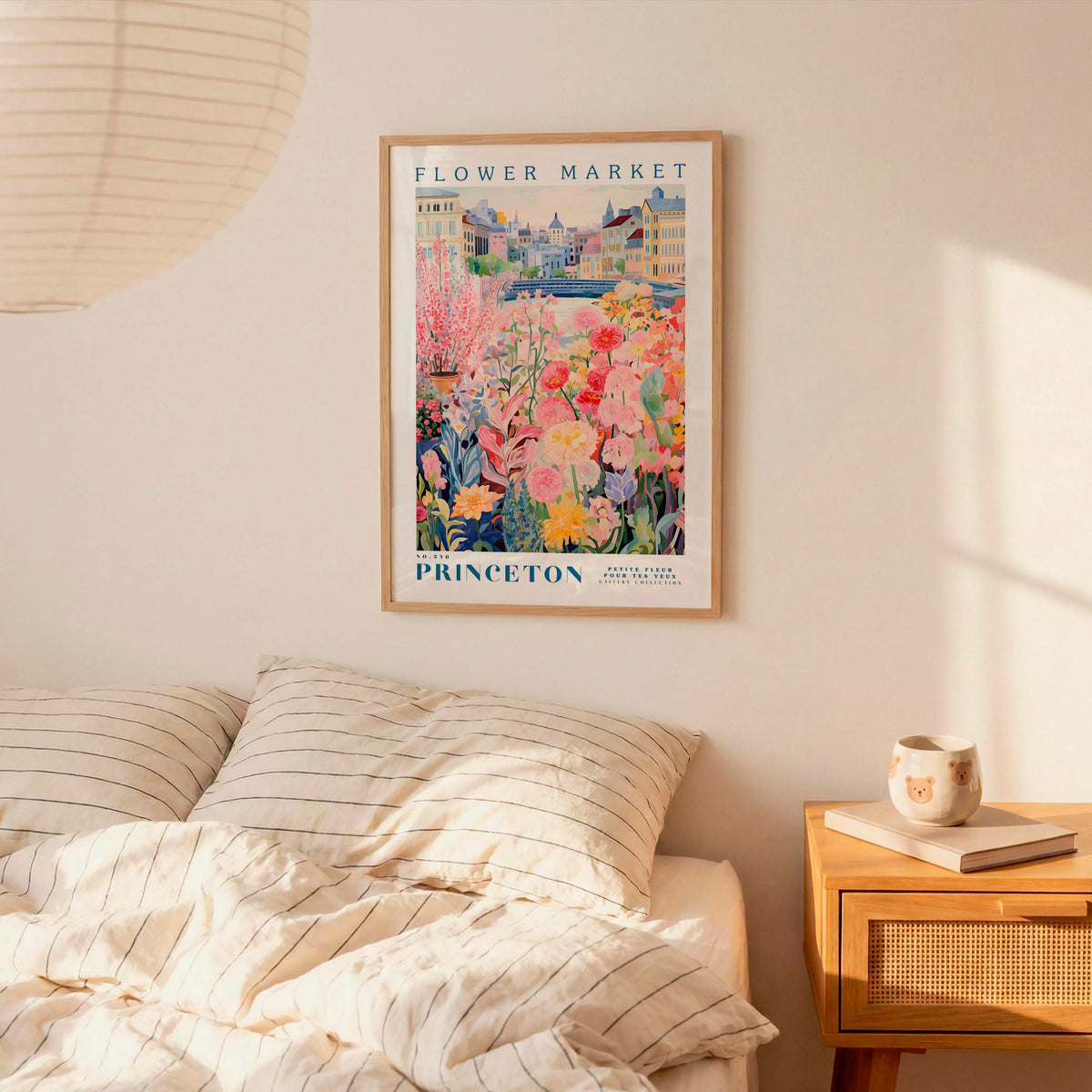 a bedroom setting with a framed poster of a colorful garden hanging on the wall above a bed with striped pillows.