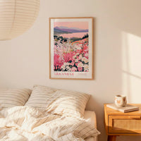 a bedroom scene with a framed poster of a floral landscape hanging on the wall above a bed with striped pillows.