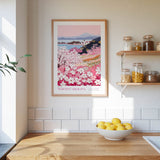 a kitchen scene with a framed poster of a flowery landscape hanging on the wall above a wooden countertop with a bowl of lemons.