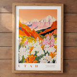 The image is a framed poster depicting a scenic landscape with mountains, flowers, and a warm, orange sky.