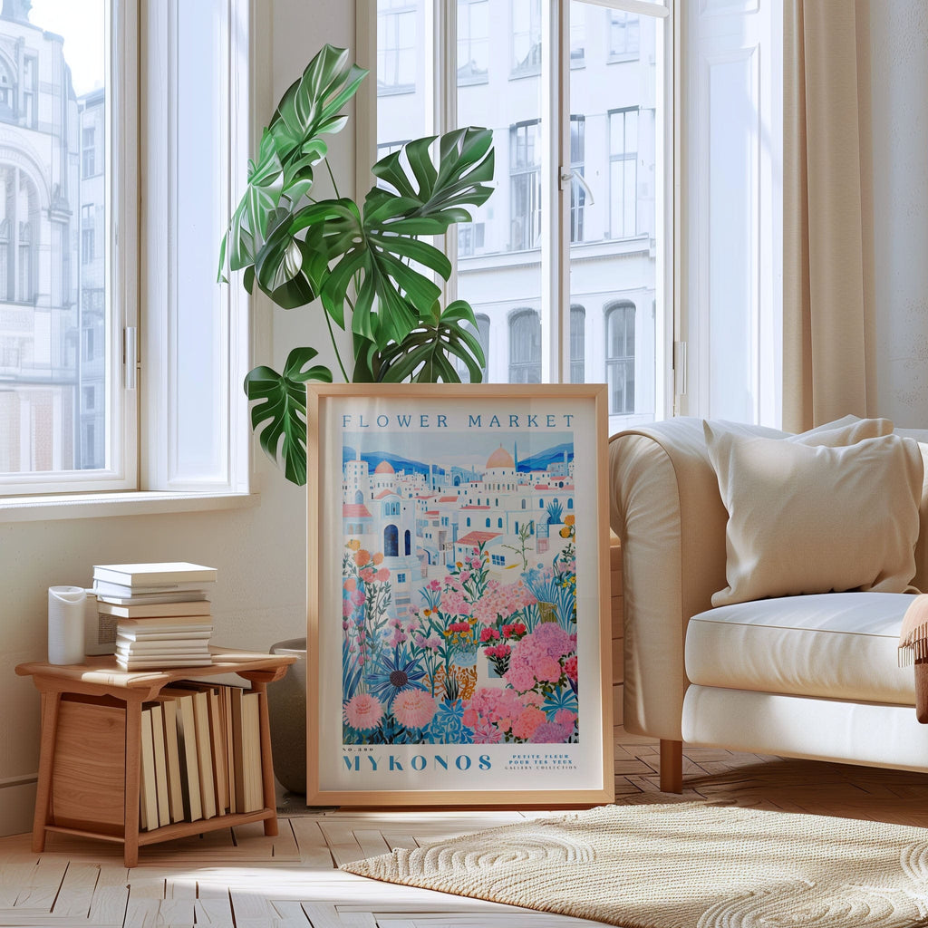 a poster of the Flower Market in Mykonos, Greece, displayed in a living room with a large window, a white sofa, and a bookshelf.