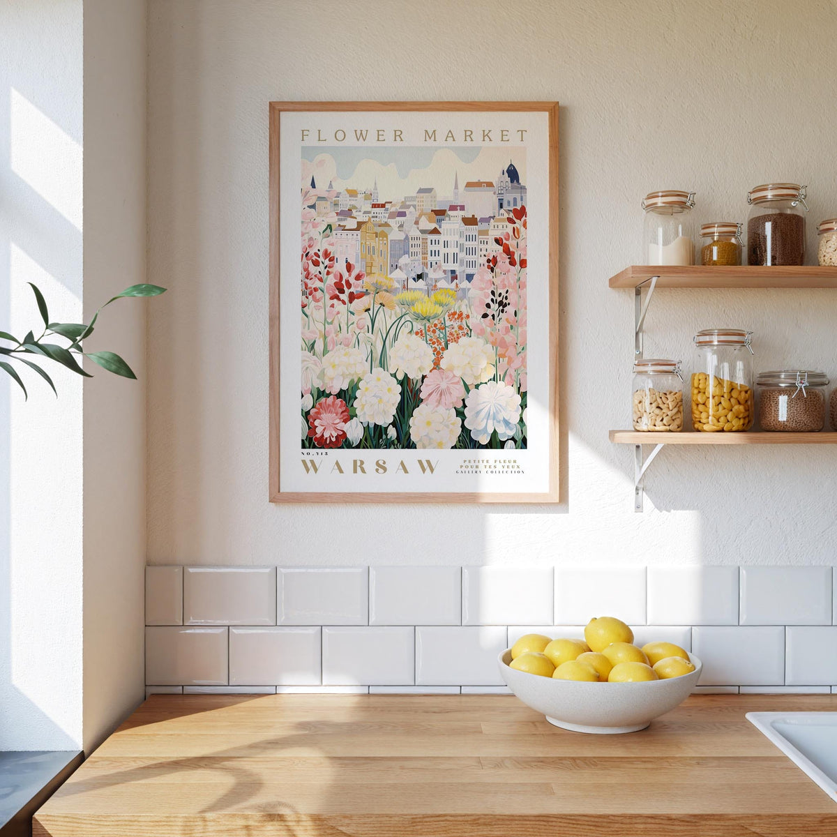 a kitchen scene with a framed poster of a flower market in Warsaw hanging on the wall above a wooden counter. On the counter, there is a bowl of lemons and a plant.