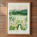 The image is a framed poster depicting a scenic landscape with mountains, a lake, and a field of flowers.
