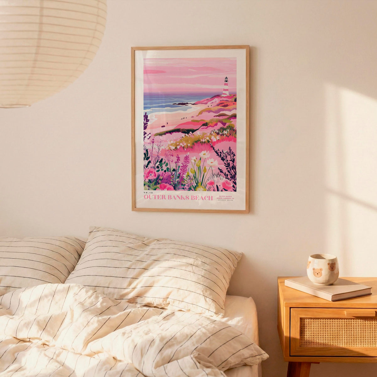 a bedroom with a bed, a nightstand, and a framed poster of a lighthouse on the wall.