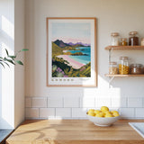 a kitchen counter with a bowl of lemons, a framed picture of a coastal landscape, and various kitchen items such as jars and a plant.