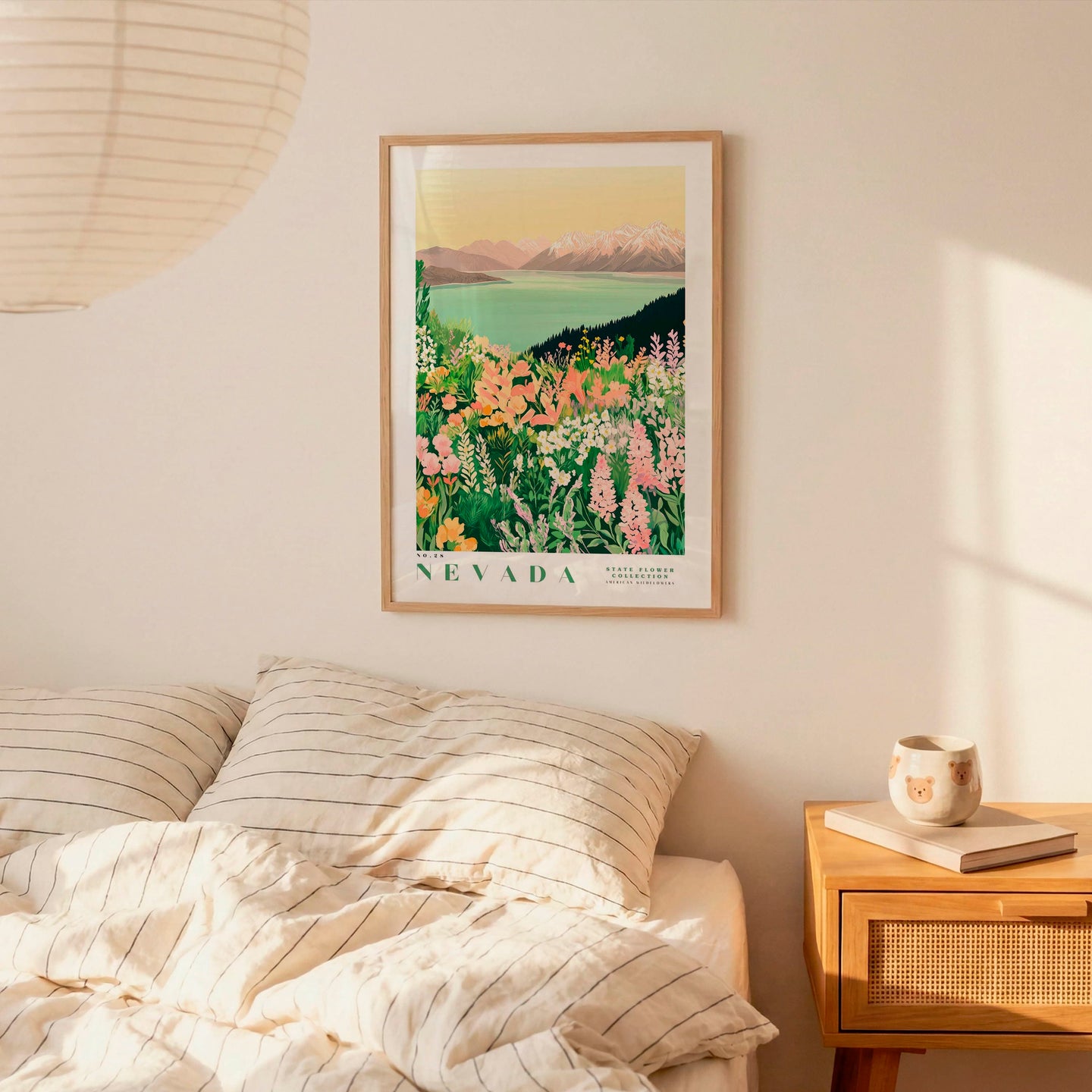 a bedroom scene with a framed poster of a colorful floral landscape hanging on the wall above a bed with striped pillows.