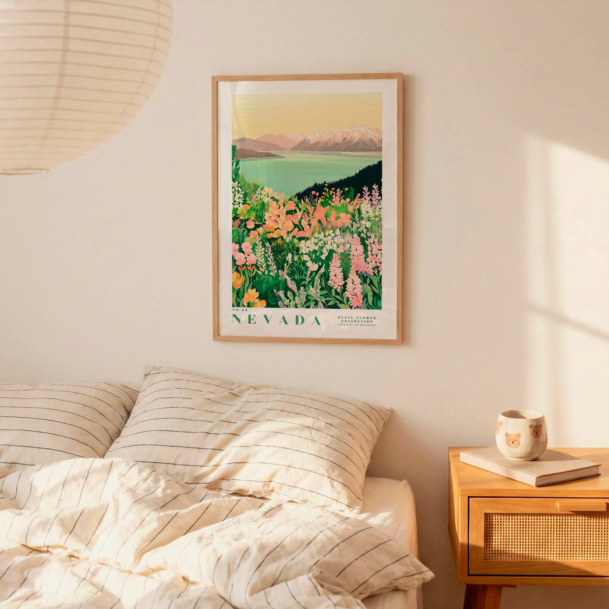 a bedroom scene with a framed poster of a colorful floral landscape hanging on the wall above a bed with striped pillows.