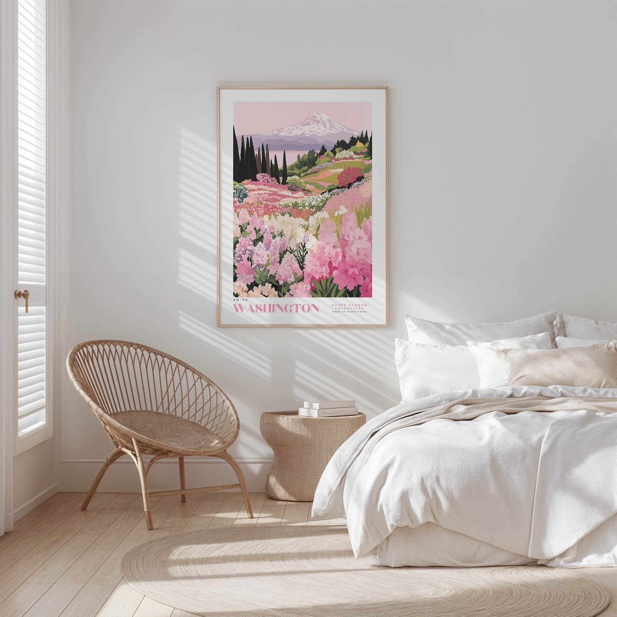 a serene bedroom scene with a bed, a woven chair, and a framed poster of a mountain landscape with pink flowers hanging on the wall.