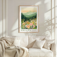 a framed poster of a mountain landscape with flowers hanging on a wall above a white couch with a blanket draped over it.