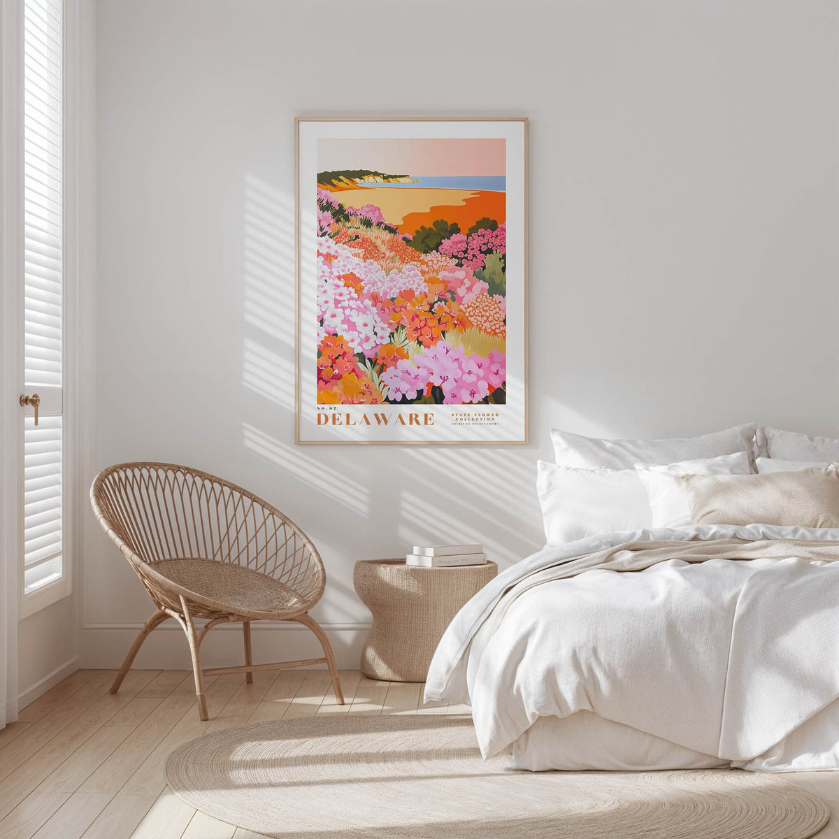 A bedroom with a large bed, a woven chair, and a framed poster of a colorful floral landscape hanging on the wall.