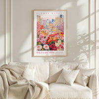 a framed poster of a vibrant cityscape with a variety of colorful flowers, hanging on a wall above a white couch.