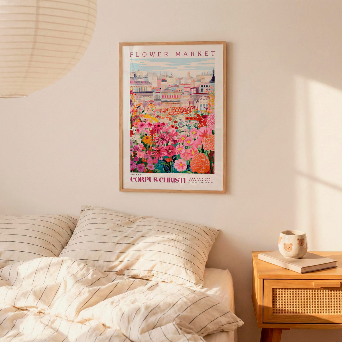 a bedroom scene with a framed poster of a colorful flower market hanging on the wall above a bed with striped bedding.