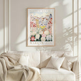 a framed poster of a flower market in Warsaw, Poland, hanging on a white wall above a white couch with a blanket draped over it.