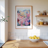 a framed poster of a colorful floral scene hanging on a wall above a kitchen counter with a bowl of lemons and jars of food.