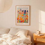 a bedroom scene with a framed poster of a cityscape hanging on the wall above a bed with striped pillows.