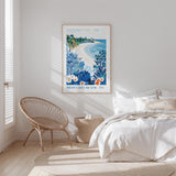 a serene bedroom scene with a large framed poster of a beach on the wall, a wicker chair, and a bed with white bedding.