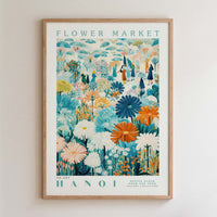 The image is a framed poster depicting a vibrant and colorful flower market scene in Hanoi, Vietnam.