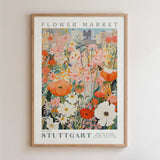 The image is a framed poster depicting a vibrant and colorful floral scene, with various flowers and plants arranged in a visually appealing manner.
