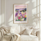 a framed poster of a colorful garden scene with flowers and a cityscape in the background, hanging on a wall above a white couch.