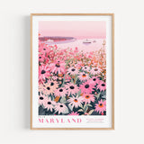 A framed poster depicting a field of pink and white flowers, with a body of water and boats in the background.