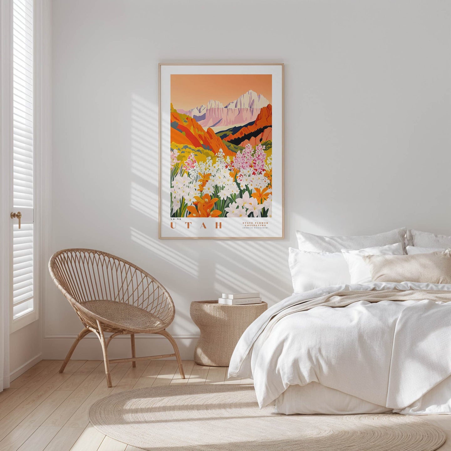 a serene bedroom scene with a large framed poster of a mountain landscape hanging on the wall, a woven chair, and a bed with white bedding.