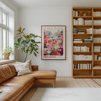 a cozy living room with a large window, a comfortable leather couch, a bookshelf filled with books, and a framed poster of a flower market in Greensboro.