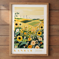 A framed print depicting a field of sunflowers and other flowers, with wind turbines visible in the background, set against a yellow sky.