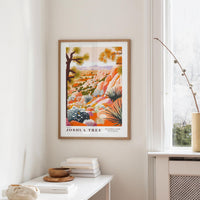 a framed poster of a desert landscape, hanging on a wall in a room with a white table and a window.
