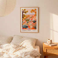 a bedroom scene with a framed poster of a desert landscape hanging on the wall above a bed with striped pillows.