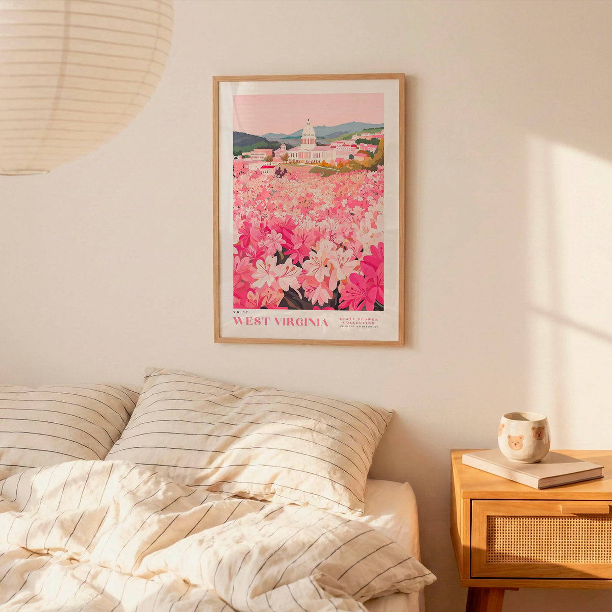 a bedroom scene with a framed poster of a flower field hanging on the wall above a bed with striped pillows.