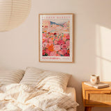 a bedroom setting with a framed poster of a flower market hanging on the wall above a bed with striped pillows.