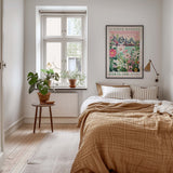 a cozy bedroom with a large bed, a nightstand with a potted plant, and a framed poster of a cityscape on the wall.