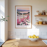 a kitchen scene with a framed poster of a flowery landscape hanging on the wall above a wooden countertop with a bowl of lemons.