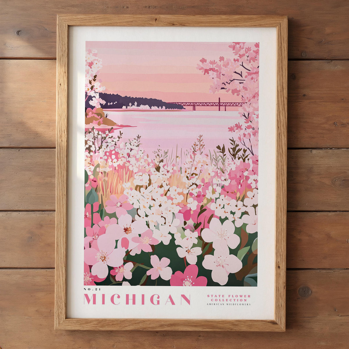 A framed poster depicting a scenic view of a lake surrounded by a field of pink and white flowers, with a bridge in the background.