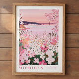 A framed poster depicting a scenic view of a lake surrounded by a field of pink and white flowers, with a bridge in the background.